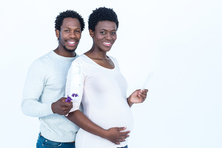 Portrait of happy husband holding paint roller while standing by wife against white bckgroundの写真素材