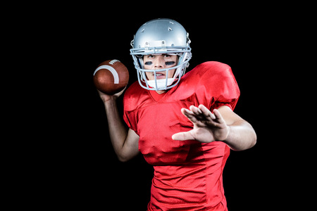 Portrait of American football player throwing ball against black backgroundの写真素材
