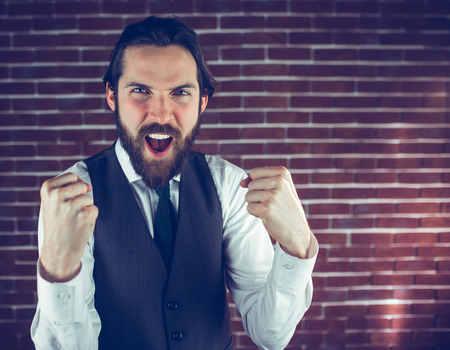 Portrait of excited hipster against brick wallの写真素材