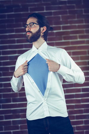 Serious man opening shirt in superhero style against a brick wallの写真素材
