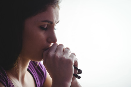 Woman praying with wooden rosary beads  on white backgroundの写真素材