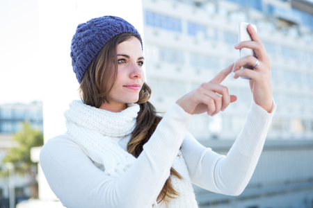 Cold brunette in warm clothes taking photos outsideの写真素材