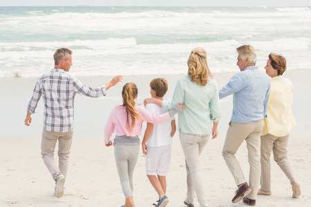 Multi generation family walking by the shore at the beachの写真素材