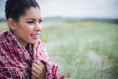 Beautiful woman wrapped up in warm clothing at the beachの写真素材