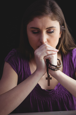 Woman praying with wooden rosary beads  on black backgroundの写真素材