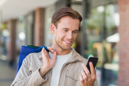 Portrait of a smiling man using his phone at the mallの写真素材