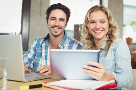 Portrait of happy colleagues working on technology in officeの写真素材