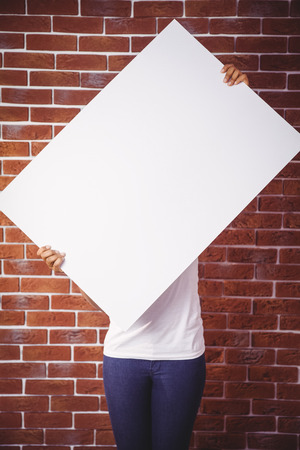 Woman holding up a white board on red brick backgroundの写真素材