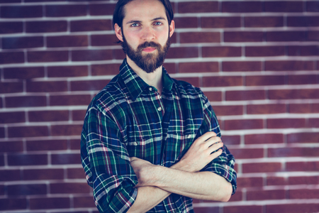 Portrait of serious confident man with arms crossed against brick wallの写真素材