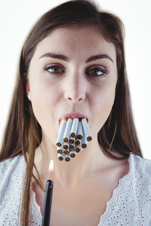 Woman lighting many cigarettes in mouth on white backgroundの写真素材