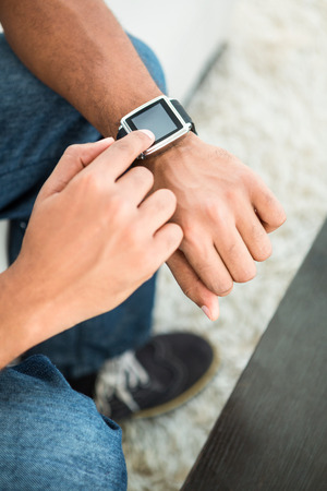 High angle view of man using smart watch at homeの写真素材