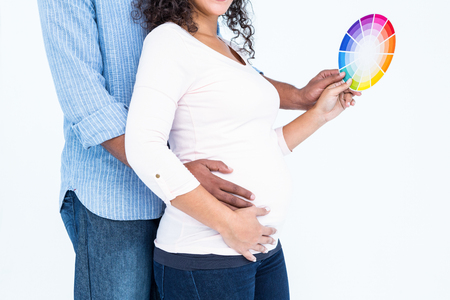 Midsection of husband with wife holding colour samples against white backgroundの写真素材