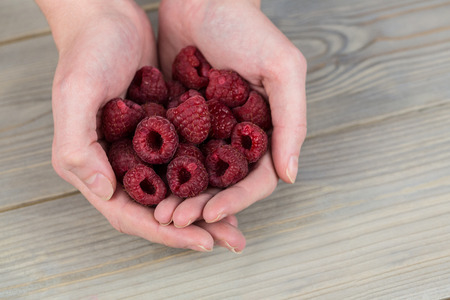 Woman showing handful of raspberries in close upの写真素材