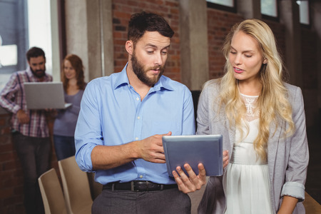 Business colleagues discussing over digital tablet in officeの写真素材