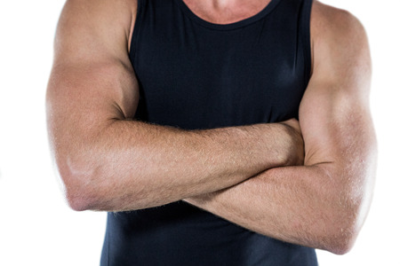 Midsection of fit athlete with arms crossed standing against white backgroundの写真素材