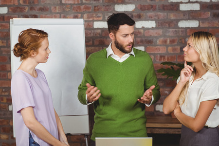 Male colleague briefing thoughtful woman in officeの写真素材