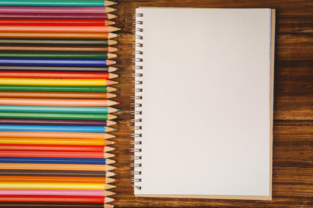 Colour pencils on desk with notepad shot in studio