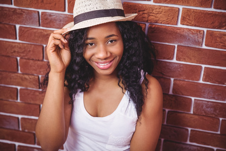 Hipster smiling at the camera on red brick backgroundの写真素材