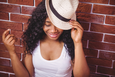 Hipster posing with a hat on red brick backgroundの写真素材