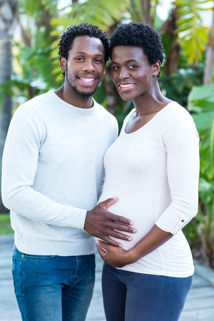 Portrait of smiling man touching woman belly while standing in parkの写真素材