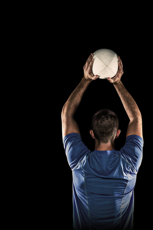 Rear view of sports player throwing ball against blackの写真素材