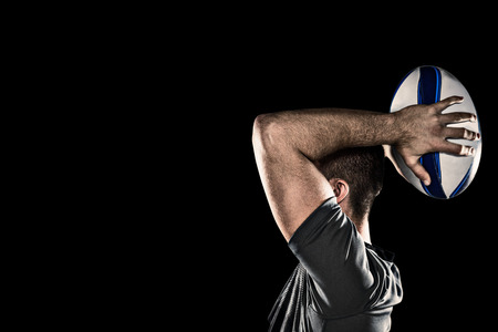 Rugby player throwing ball against blackの写真素材
