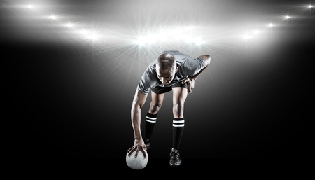 Rugby player taking position against spotlightの写真素材