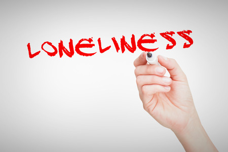 The word loneliness against female hand holding black whiteboard markerの写真素材