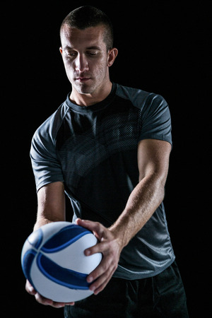 Handsome rugby player holding ball against black backgroundの写真素材