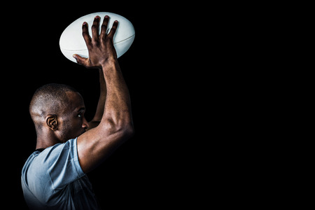 Rugby player throwing ball against blackの写真素材