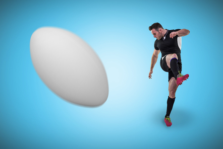 Rugby player kicking against blue background with vignetteの写真素材