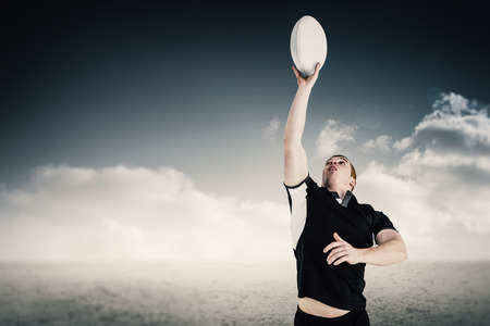 Rugby player catching a rugby ball against desert landscapeの写真素材