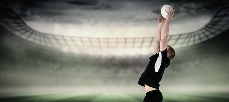 Rugby player catching a rugby ball against rugby stadiumの写真素材