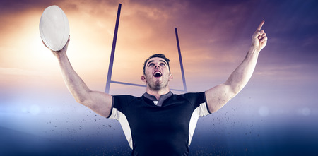 Rugby player cheering with the ball against goals postsの写真素材