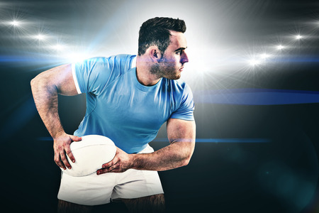 Rugby player throwing the ball against spotlightの写真素材