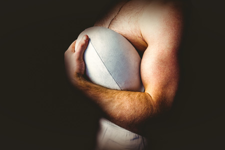 Shirtless rugby player holding ball on white backgroundの写真素材