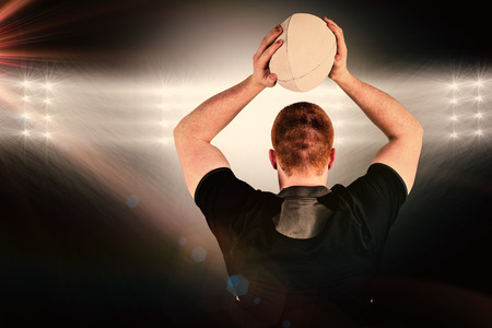 Rugby player about to throw a rugby ball against spotlightの写真素材