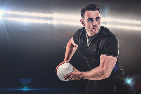Rugby player throwing the ball against spotlightの写真素材