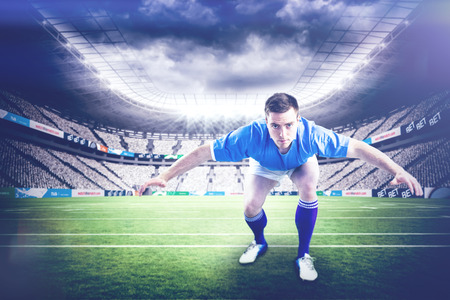 Rugby player with hands on hips against rugby stadiumの写真素材