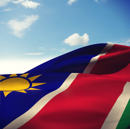 Close-up of Namibia flag waving against blue sky with cloudsの写真素材