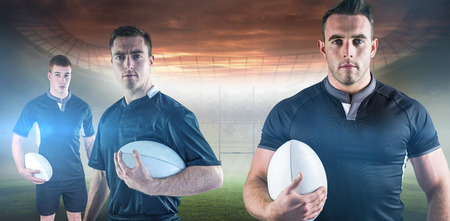 Rugby player holding a rugby ball against rugby pitchの写真素材