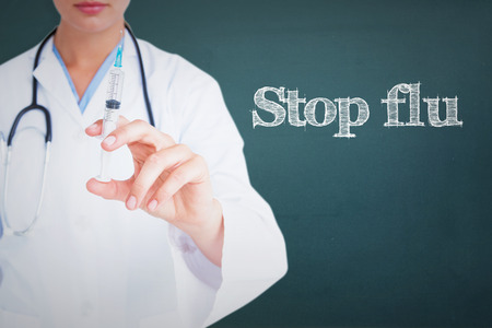 The word stop flu and doctor showing syringe to camera against chalkboardの写真素材