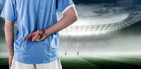 Rugby player with hands on hips against rugby stadiumの写真素材
