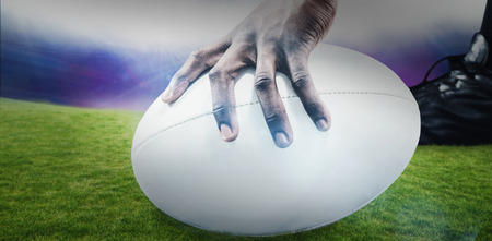 Cropped image of sportsman holding rugby ball against rugby stadiumの写真素材