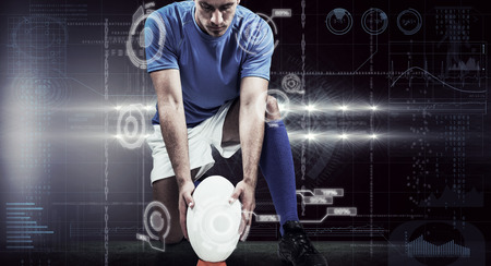 Full length of rugby player placing ball against spotlightsの写真素材