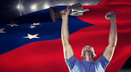 Happy rugby player holding trophy against rugby stadiumの写真素材