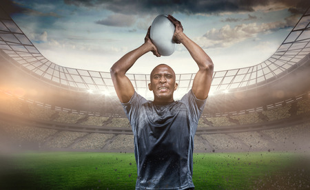 Determined sportsman throwing rugby ball against rugby stadiumの写真素材