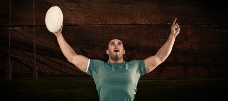 Rugby player cheering and pointing against rugby stadiumの写真素材
