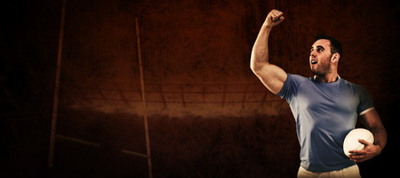 Rugby player cheering with the ball against rugby stadiumの写真素材