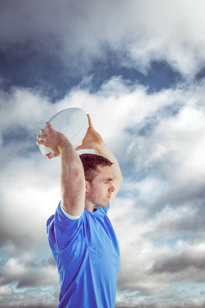 Disappointed rugby player holding his head against bright blue sky with cloudsの写真素材